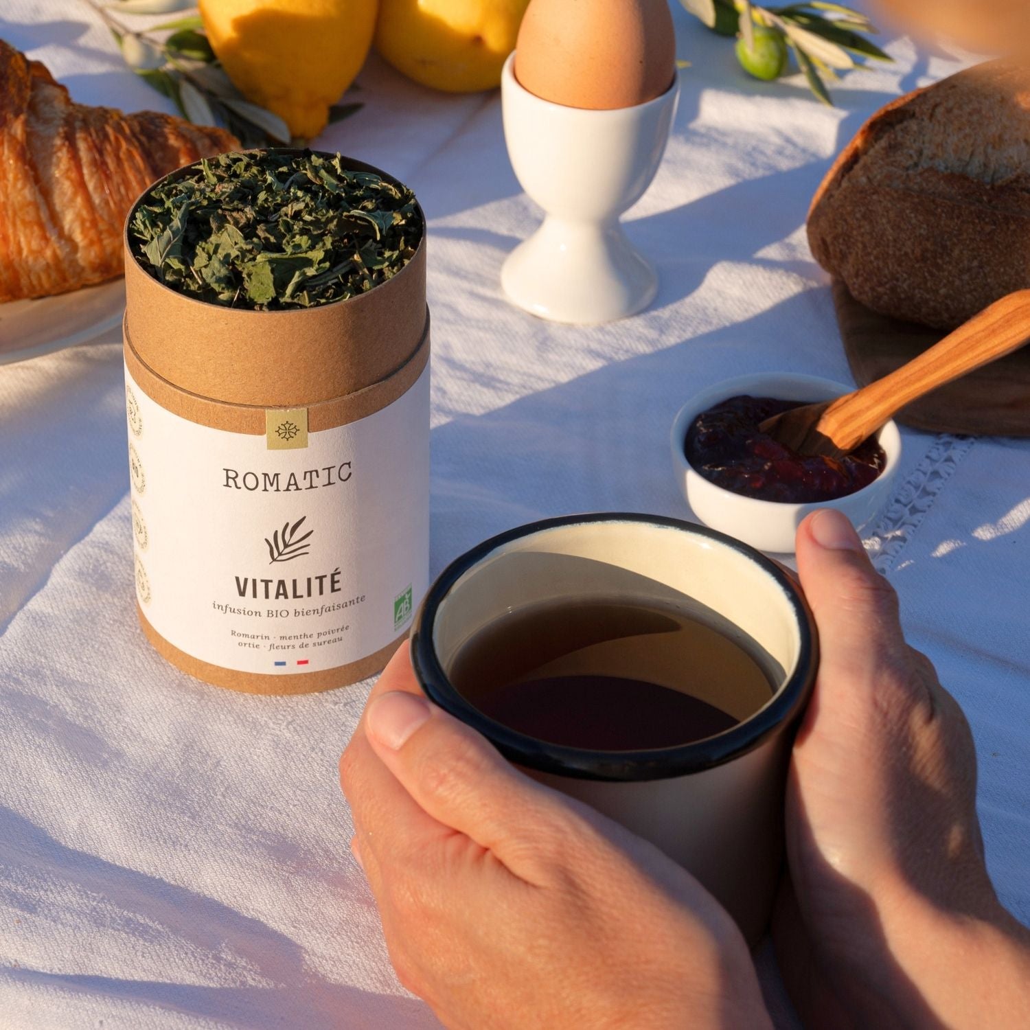 Infusion Vitalité bio – photo lifestyle avec boîte ouverte et tasse d'infusion en main
