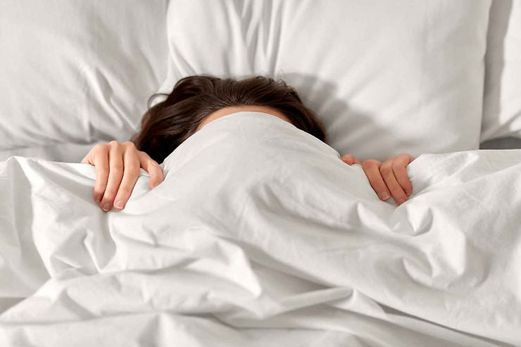 Visage de femme cachée sous sa couette