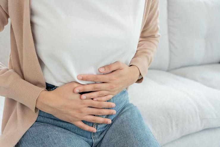 Femme assise sur un canapé qui souffre d'une digestion lente
