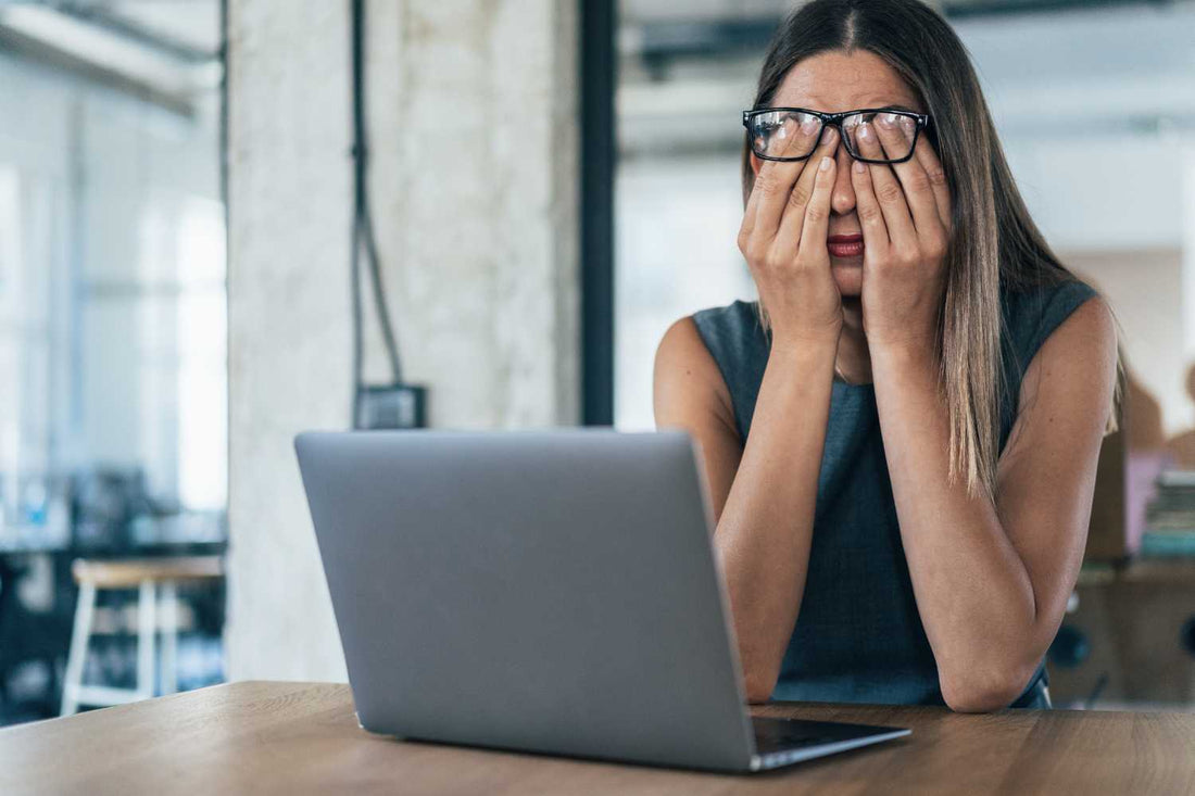 Femme fatiguée assise à son bureau qui se frotte les yeux