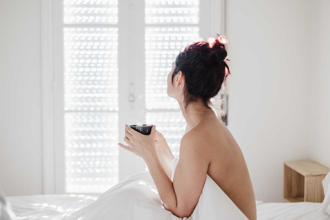 Femme au lit avec une tasse de tisane