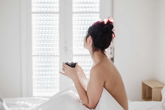 Femme au lit avec une tasse de tisane