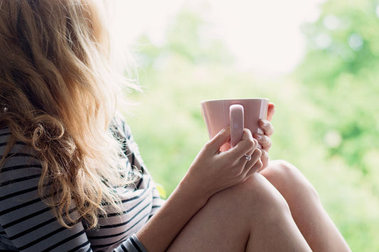 Femme sereine buvant une tasse de tisane aux plantes anti-stress