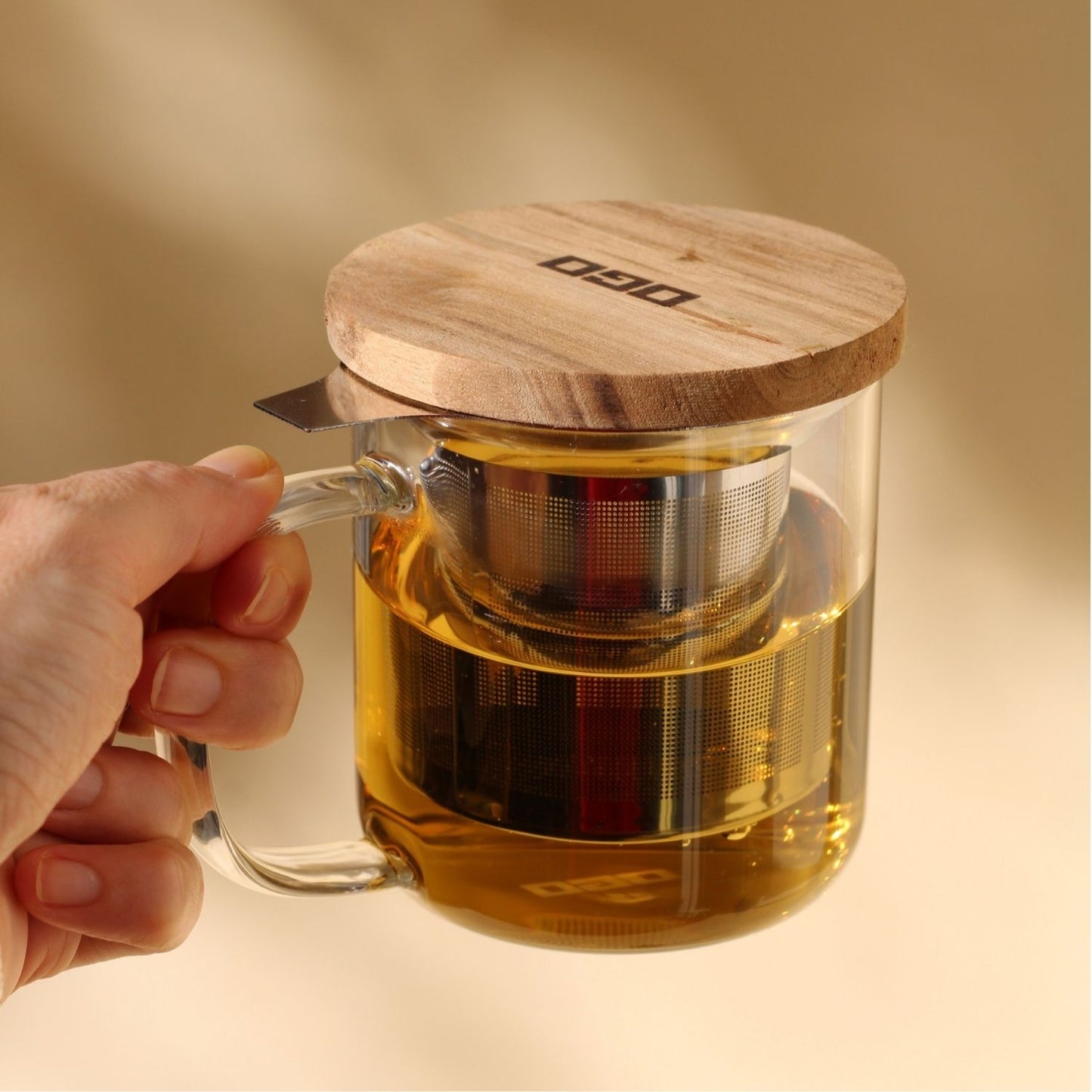 Tisanière en verre avec filtre intégré prise en main avec une infusion